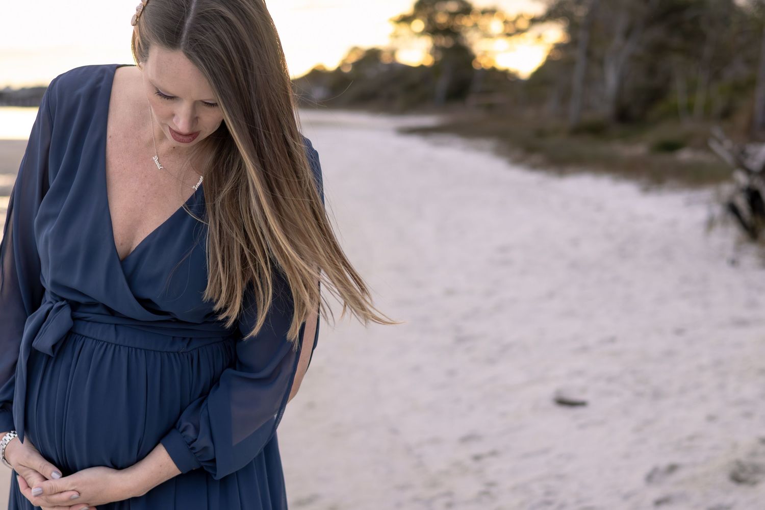 Maternity photo of a mom in a navy dress by the bay