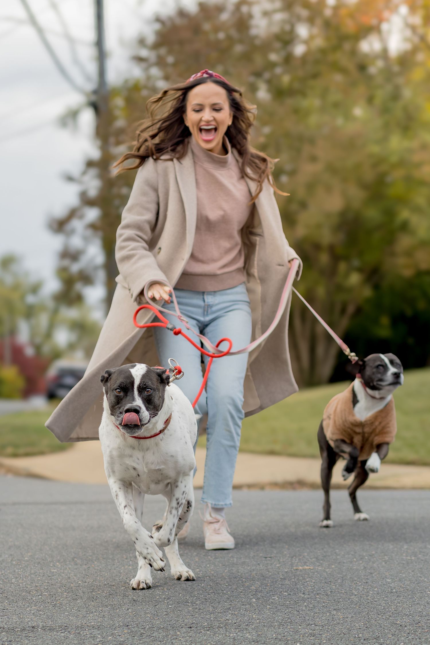 Woman laughing while walking her two dogs on a leash