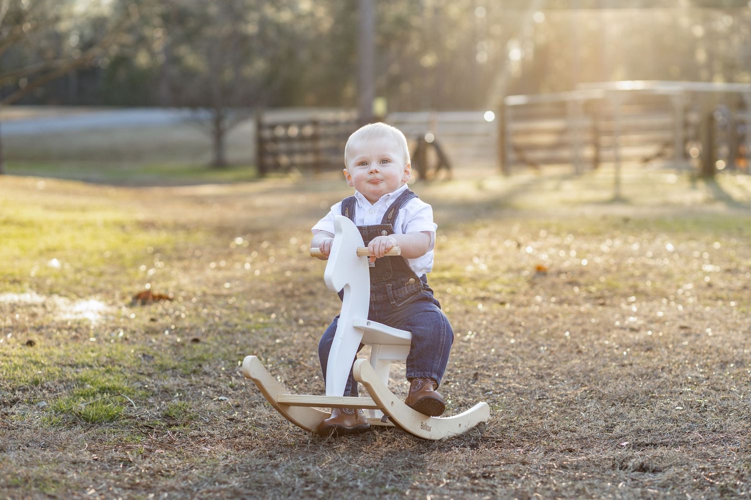 Toddler riding a wooden rocking horse outdoors at golden hour