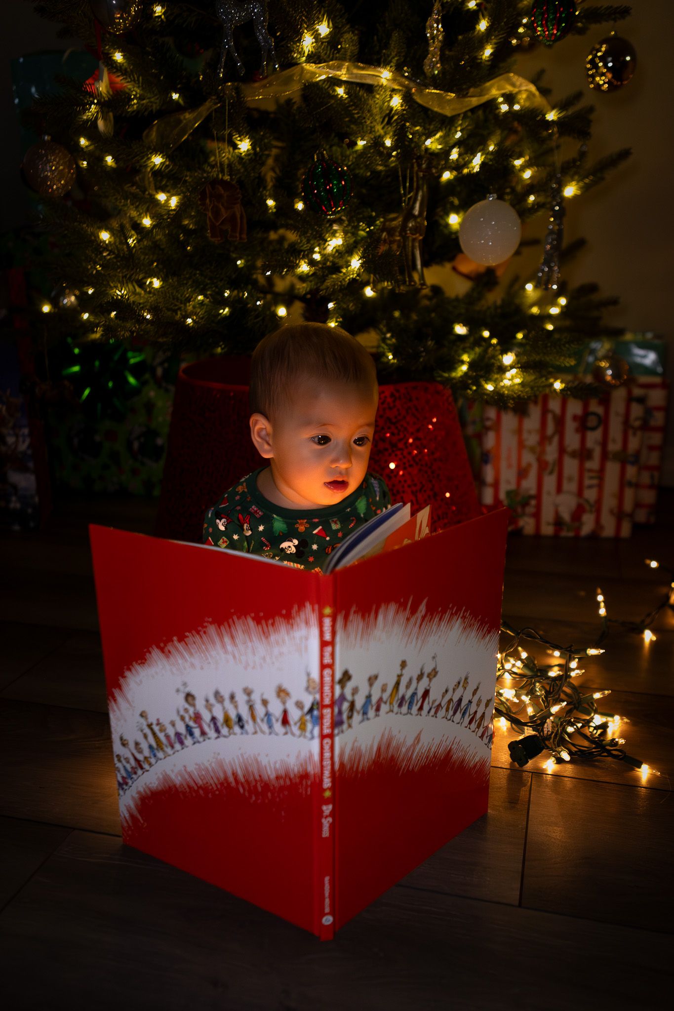 Toddler peeking out of a wrapped Christmas box by the tree