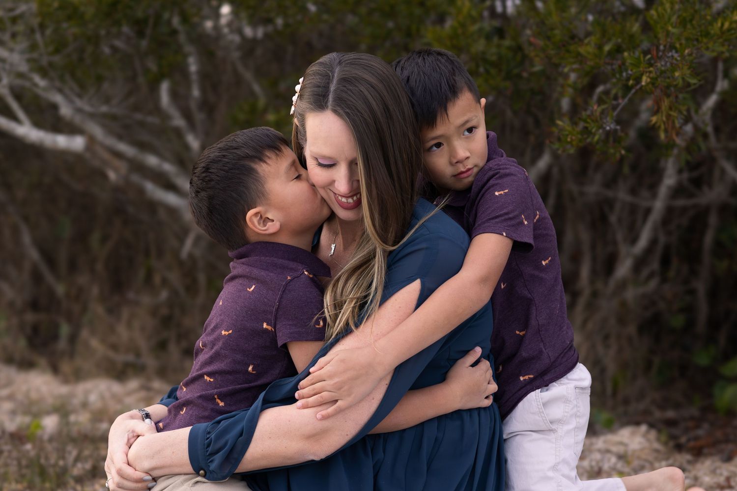 Pregnant mom hugging her two young sons outdoors