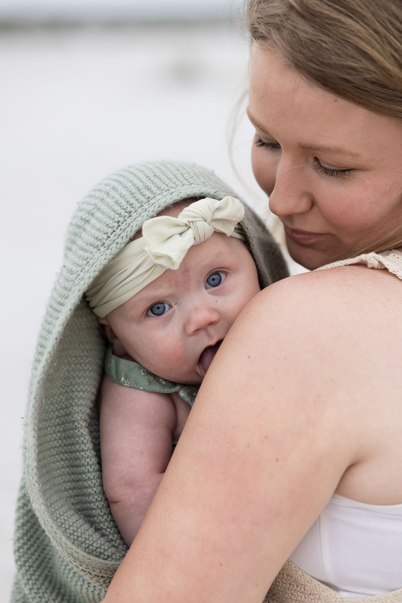 Mom snuggling her baby wrapped in a hooded towel on Pensacola Beach