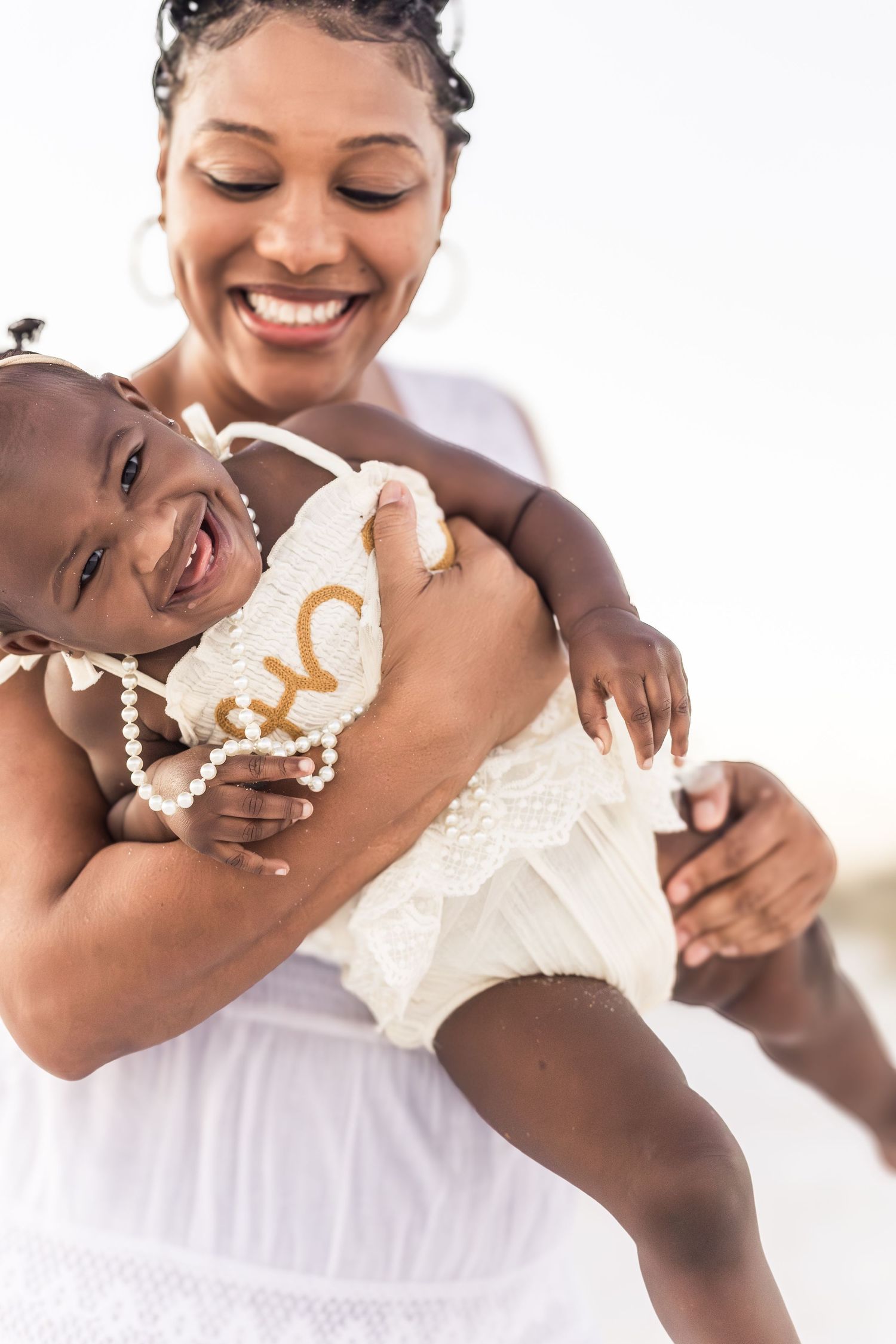 Mom laughing while holding her baby girl, first birthday photos