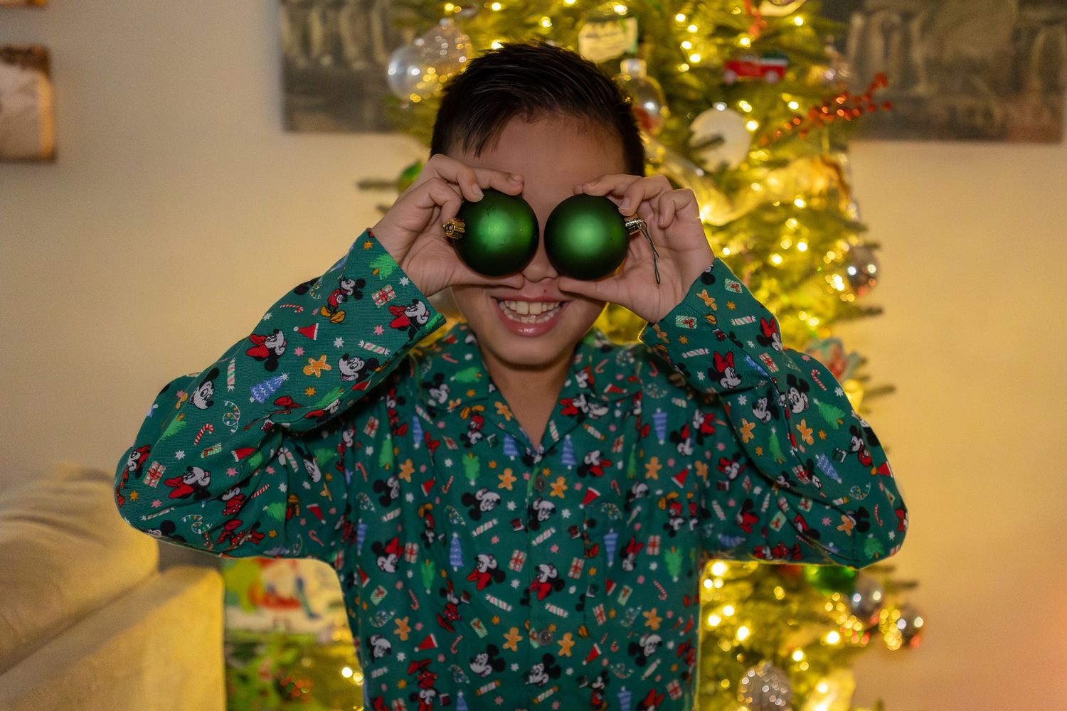 Boy in Christmas pajamas peeking through toy binoculars