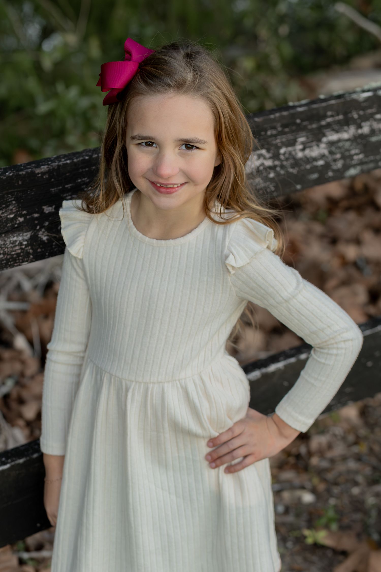 Smiling girl in a cream dress with a pink bow