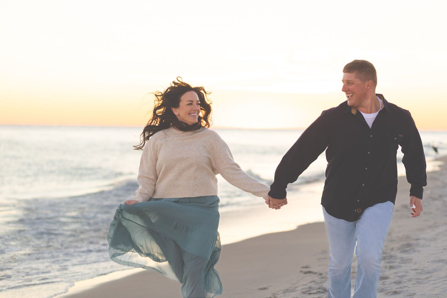 Couple walking hand in hand along the shoreline at sunset