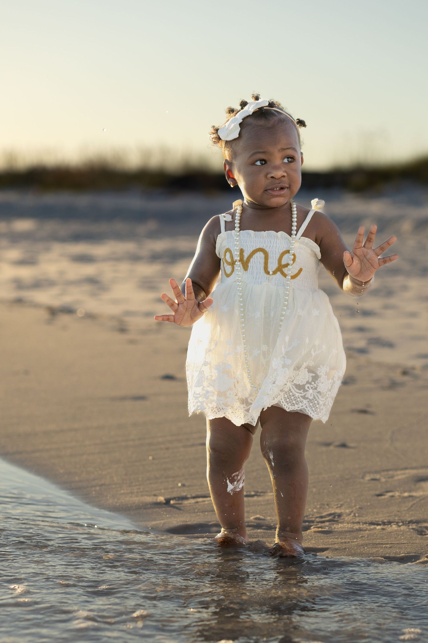 One-year-old girl walking on the beach at golden hour