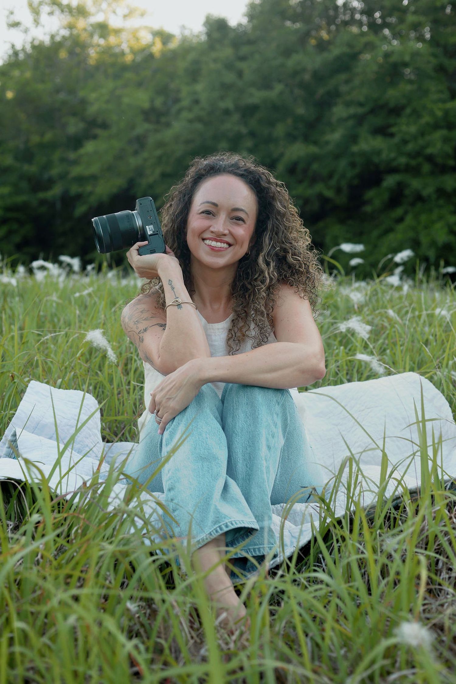 Photographer Jessica Hope smiling in a field of wildflowers with her camera