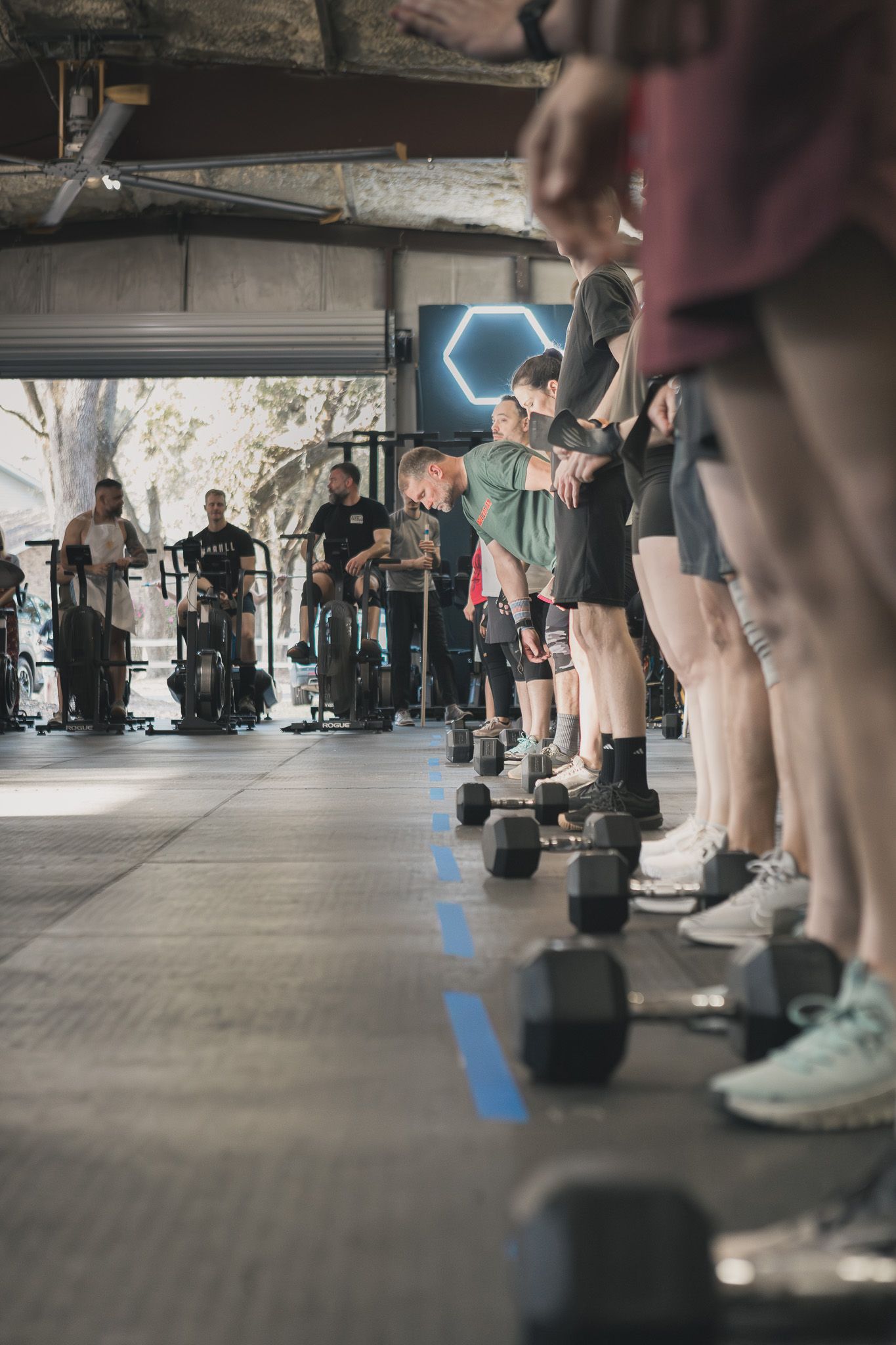 Row of athletes lined up with dumbbells during a gym competition