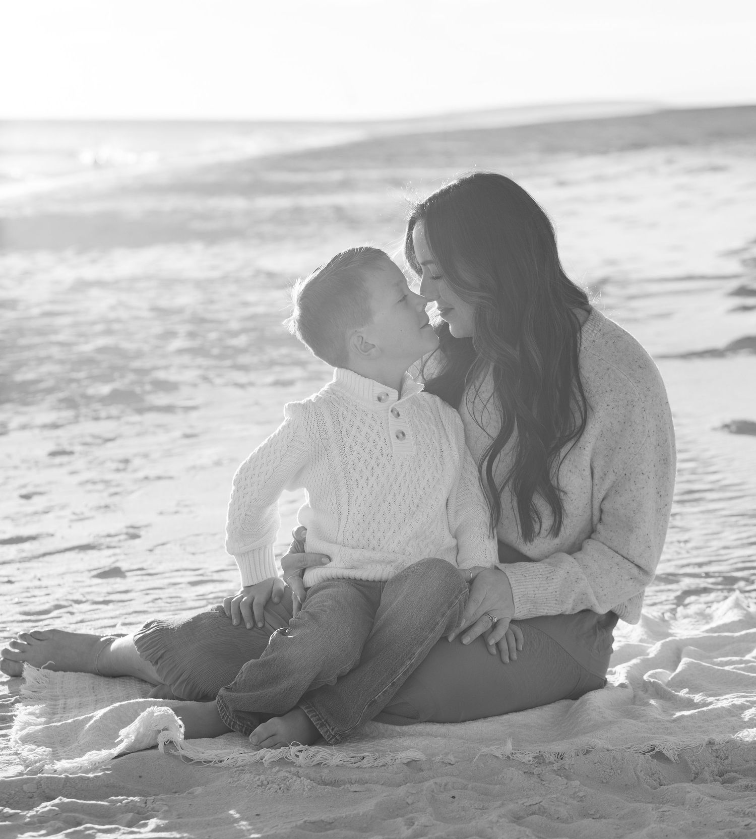 Black and white photo of a couple sitting close together in the sand