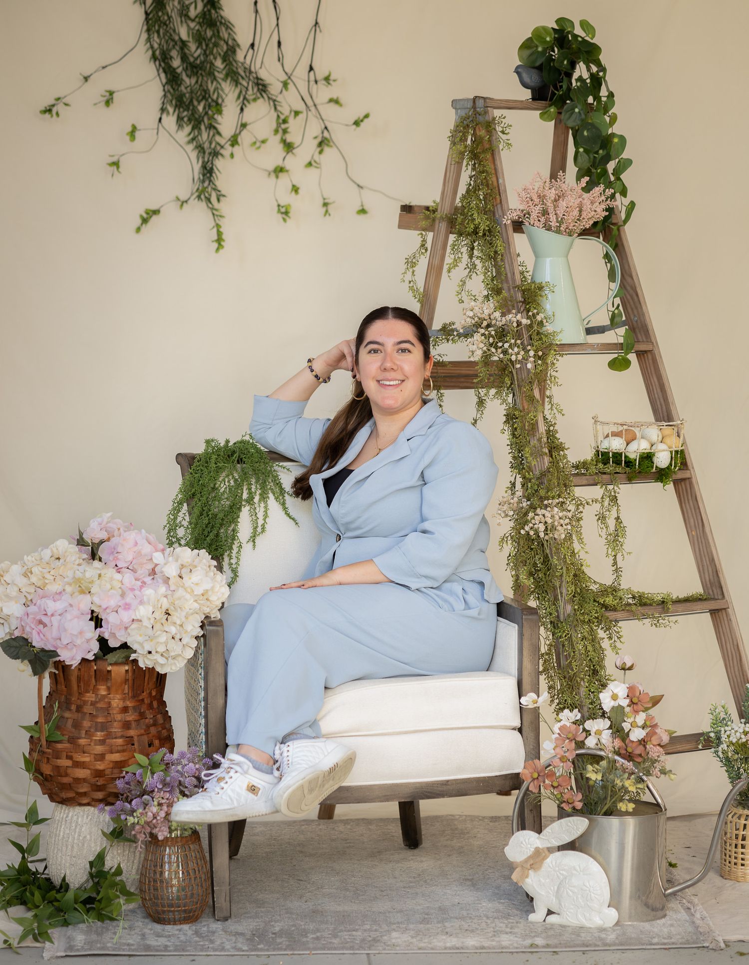 Woman posing in a spring photo booth setup with florals and a ladder