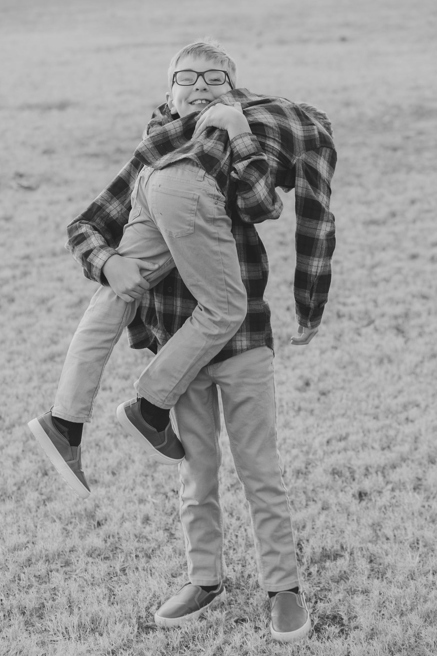 Black and white photo of a dad carrying his son on his back