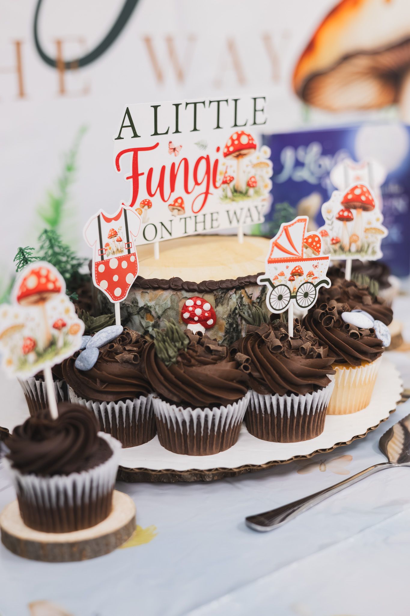 Woodland-themed cupcakes and dessert table at a baby shower