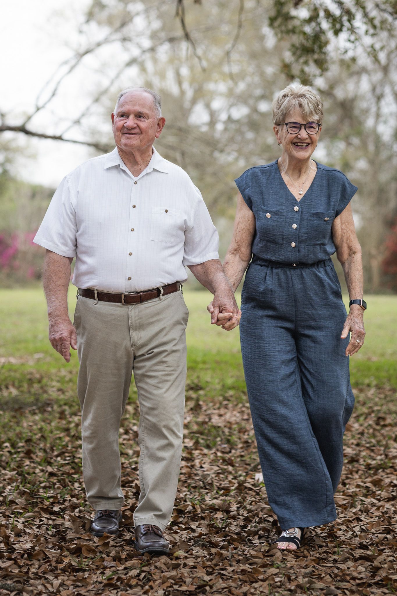 Senior couple walking hand in hand under the trees