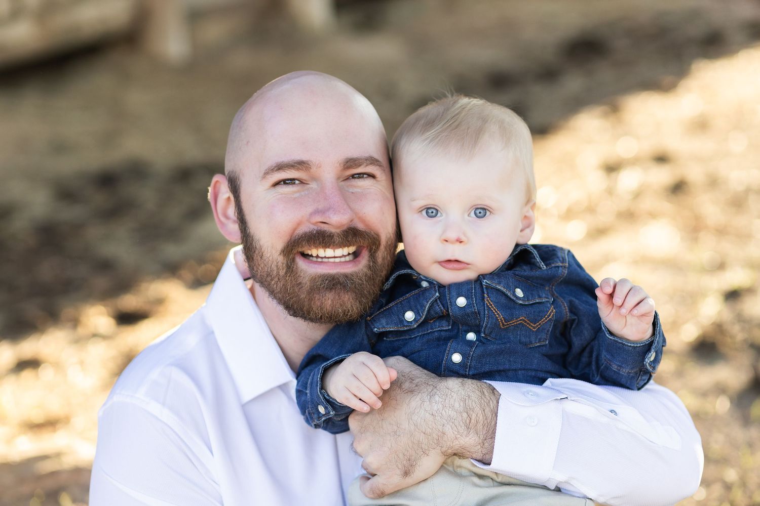 Dad smiling with his baby son on his lap outdoors