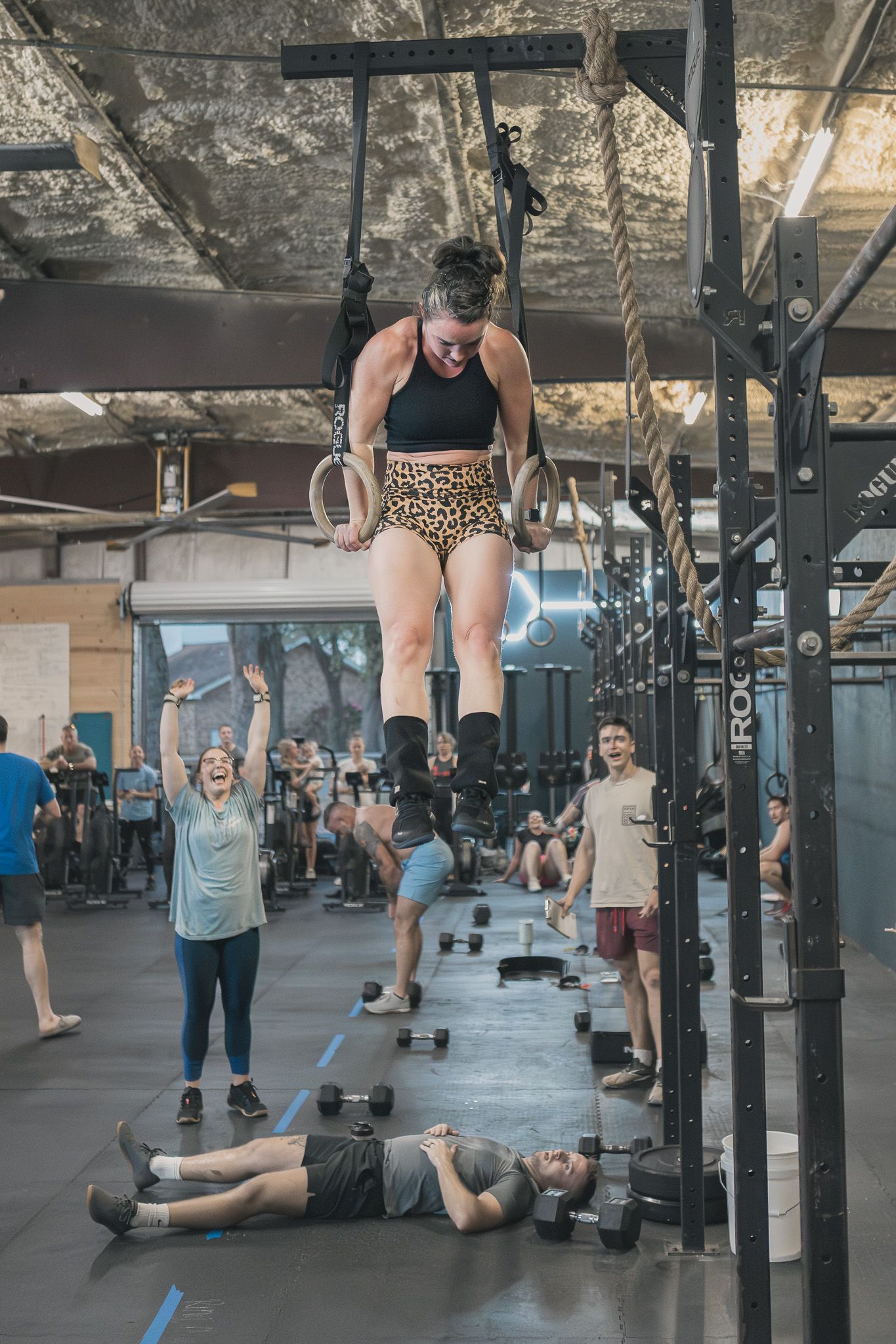 Athletes working out on rings and floor at a CrossFit gym event