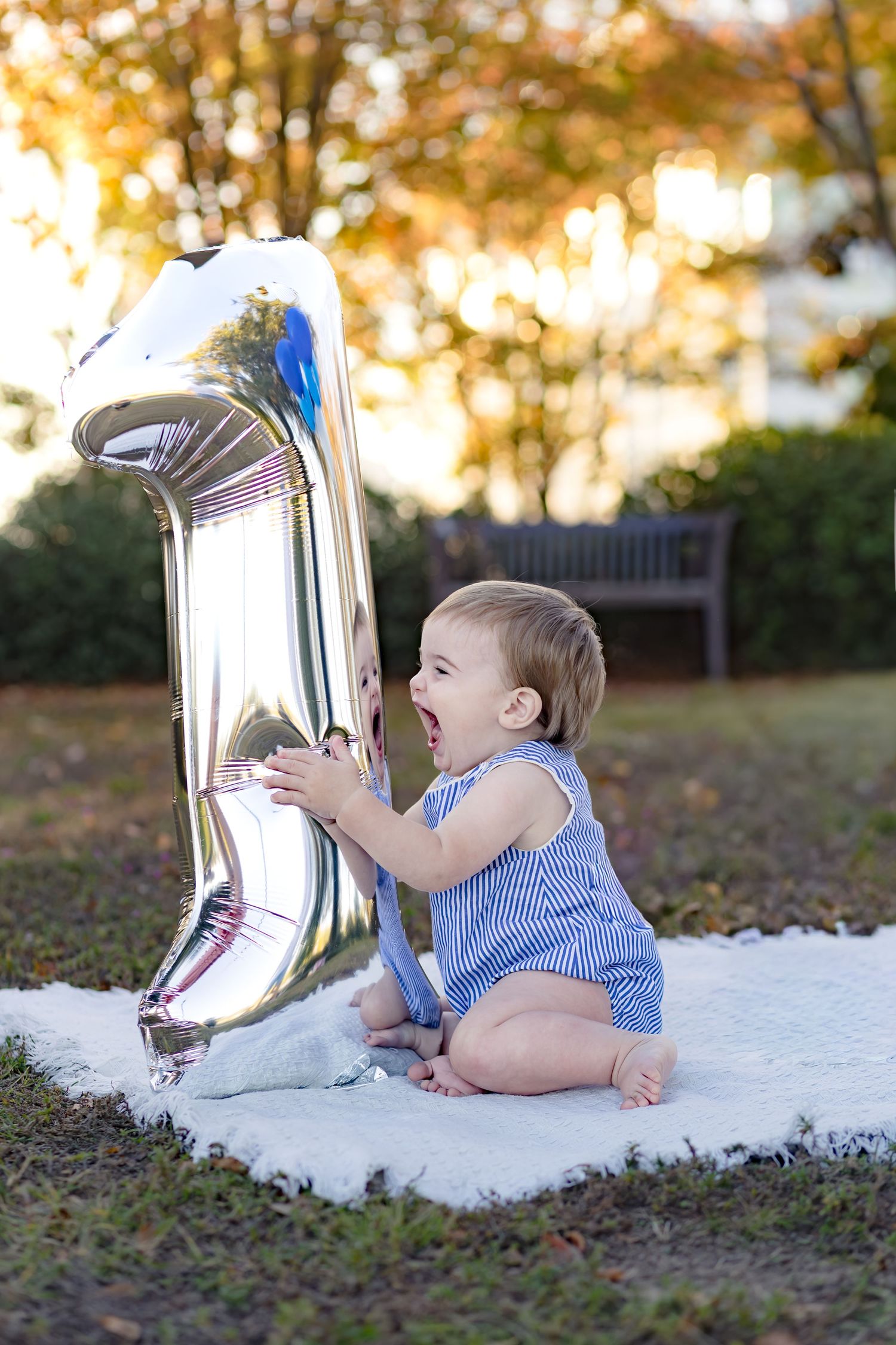 Baby girl sitting next to a silver number one balloon for her first birthday