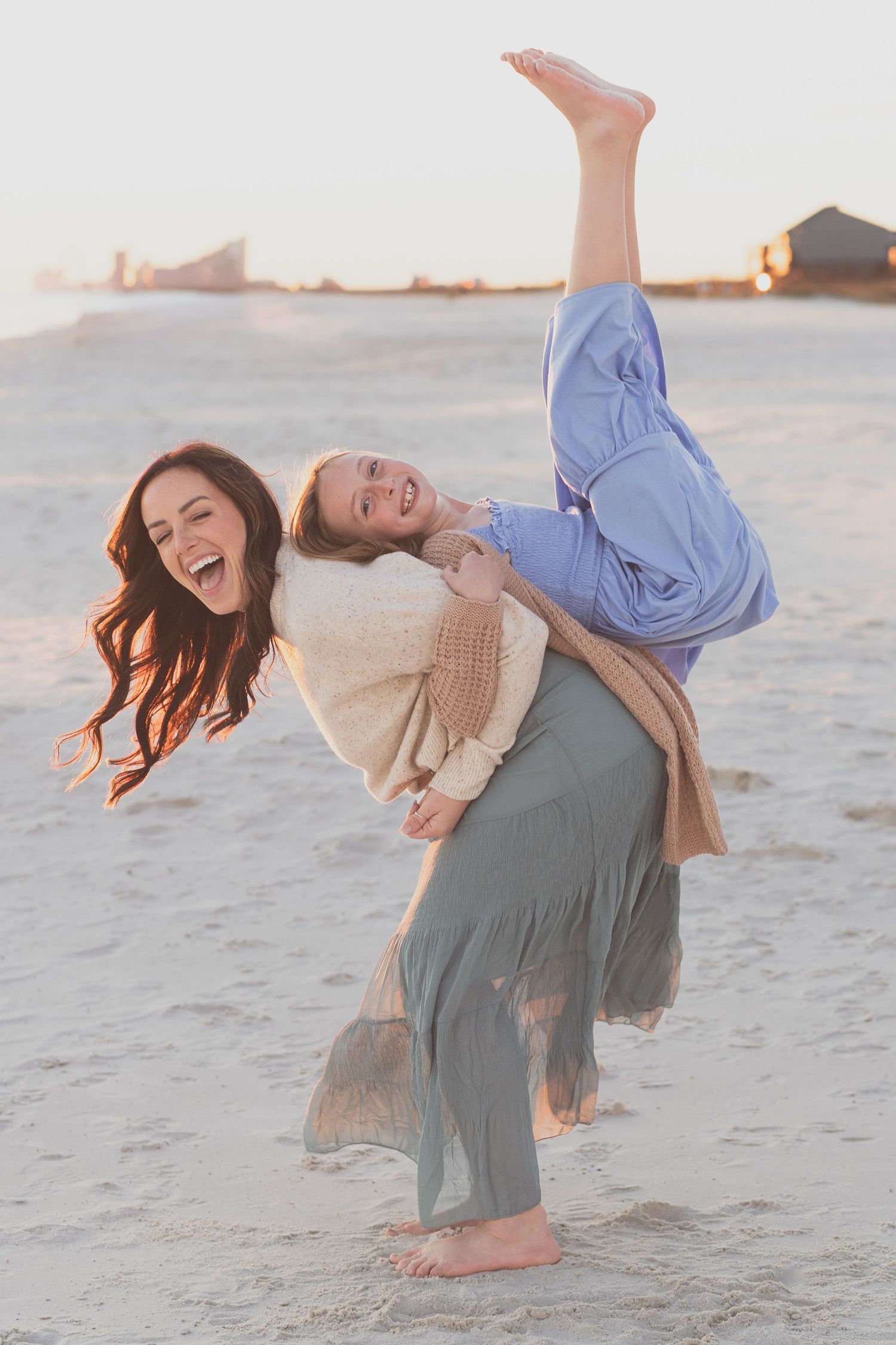 Mother and daughter laughing and dancing on the beach