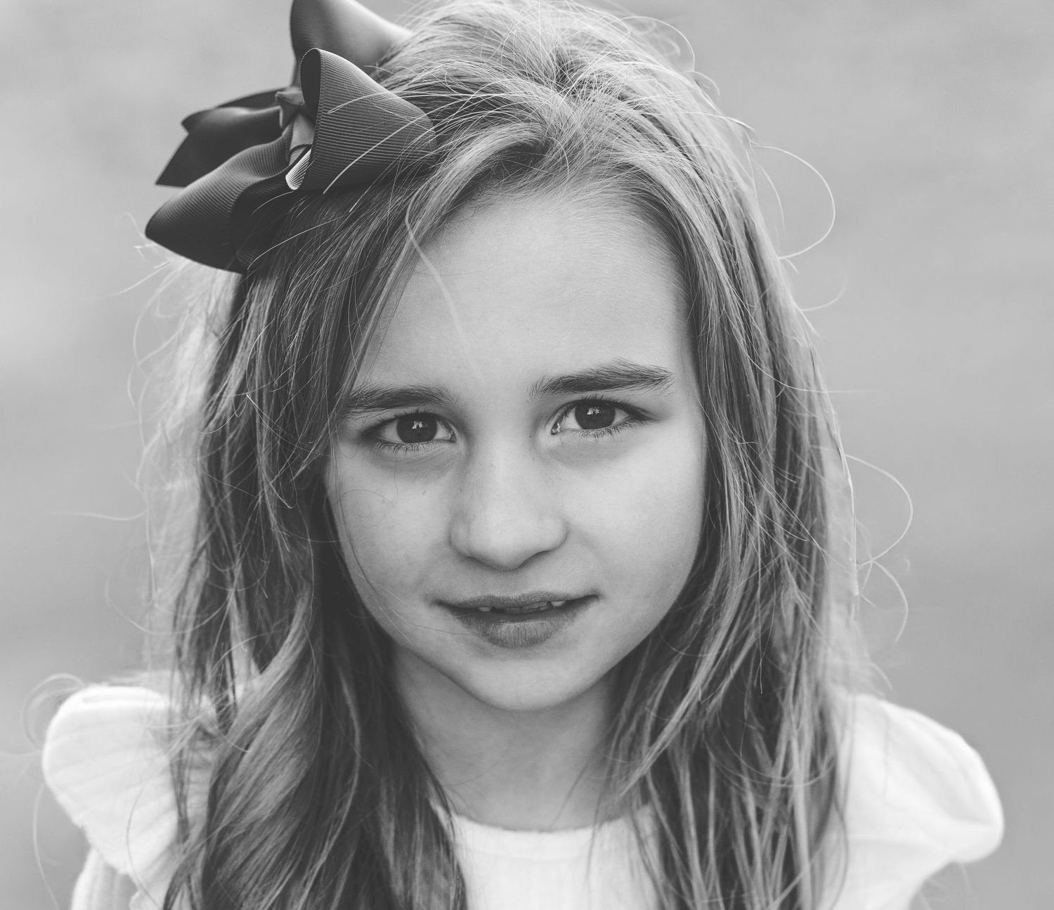 Black and white portrait of a young girl with a hair bow
