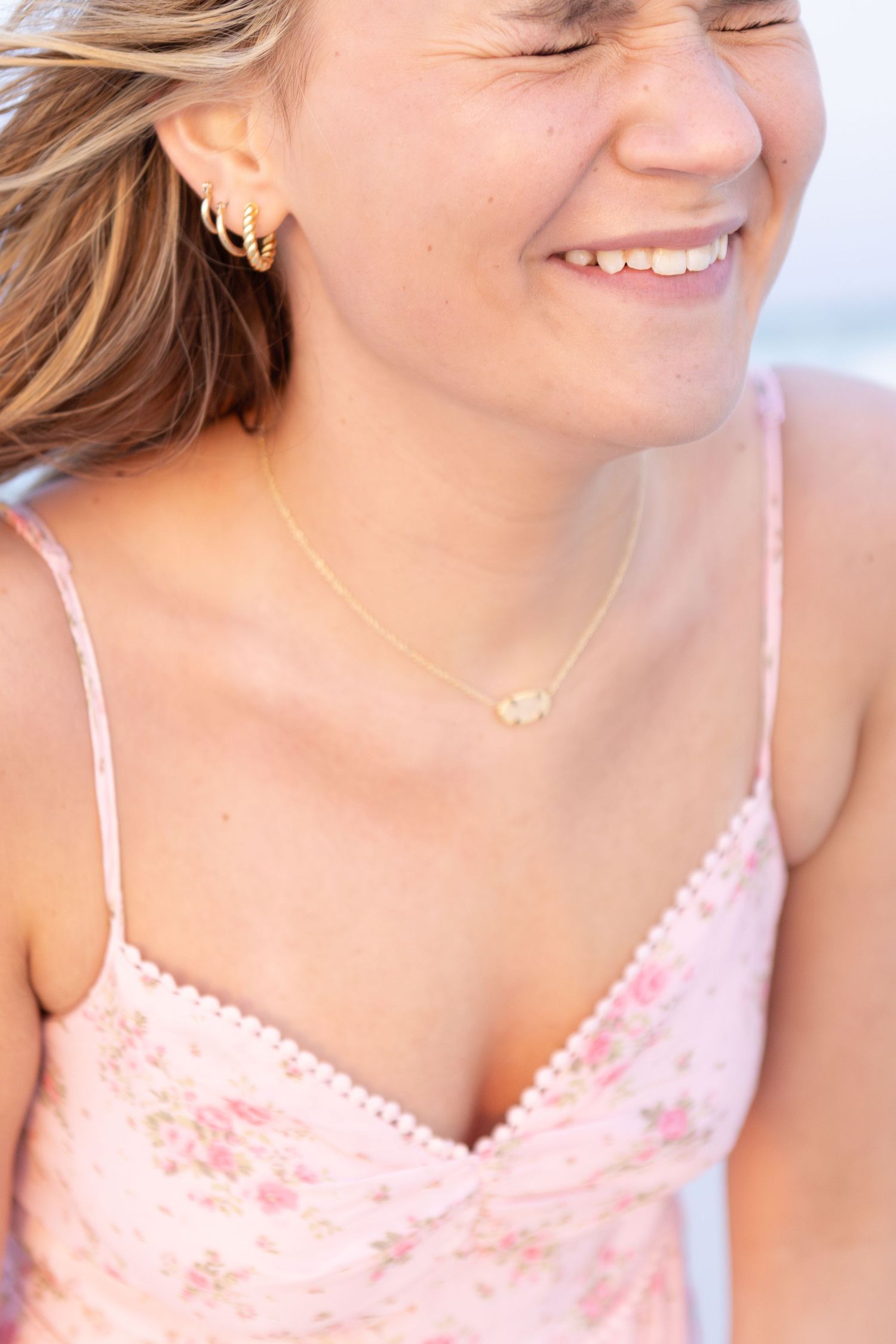 Young woman laughing on the beach in a pink sundress