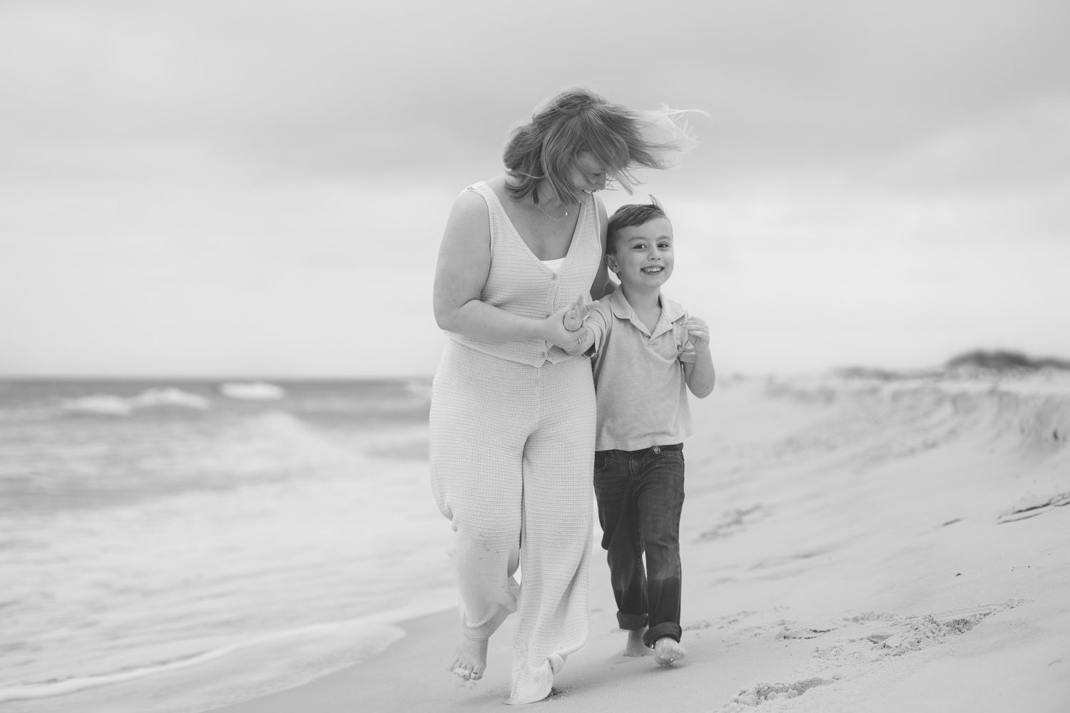 Black and white photo of a mom and son walking on Pensacola Beach