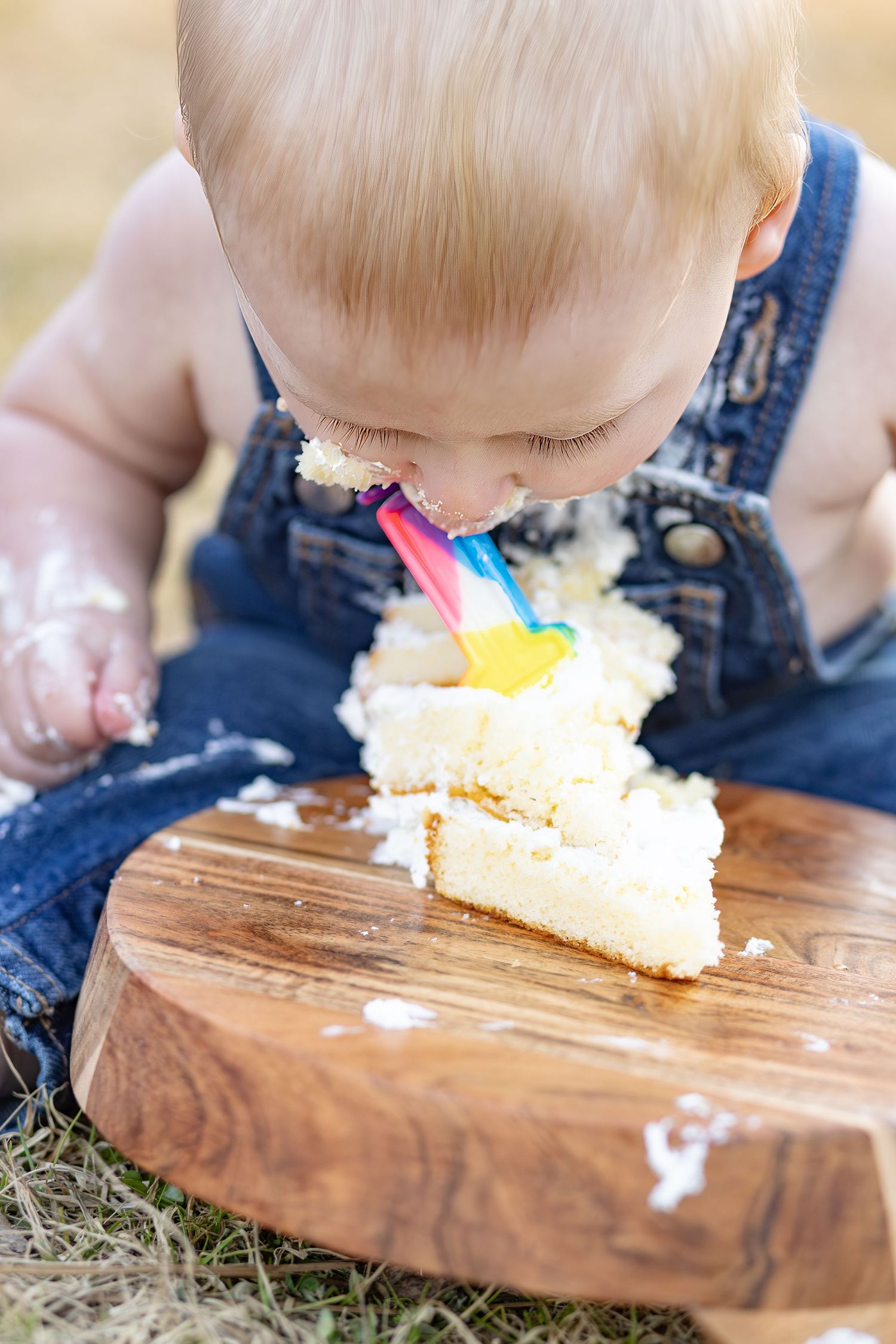 Baby boy digging into a rainbow smash cake