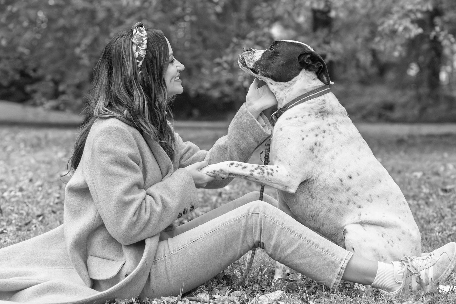 Black and white photo of a woman sitting in the grass with her dog