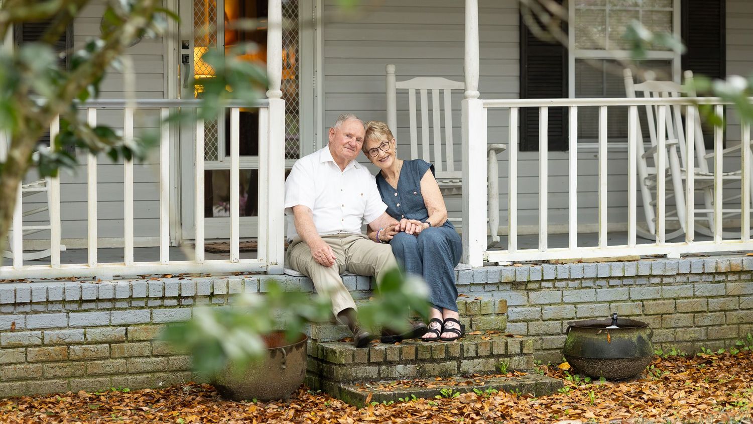 Grandparents sitting together on their porch steps in Pensacola, FL