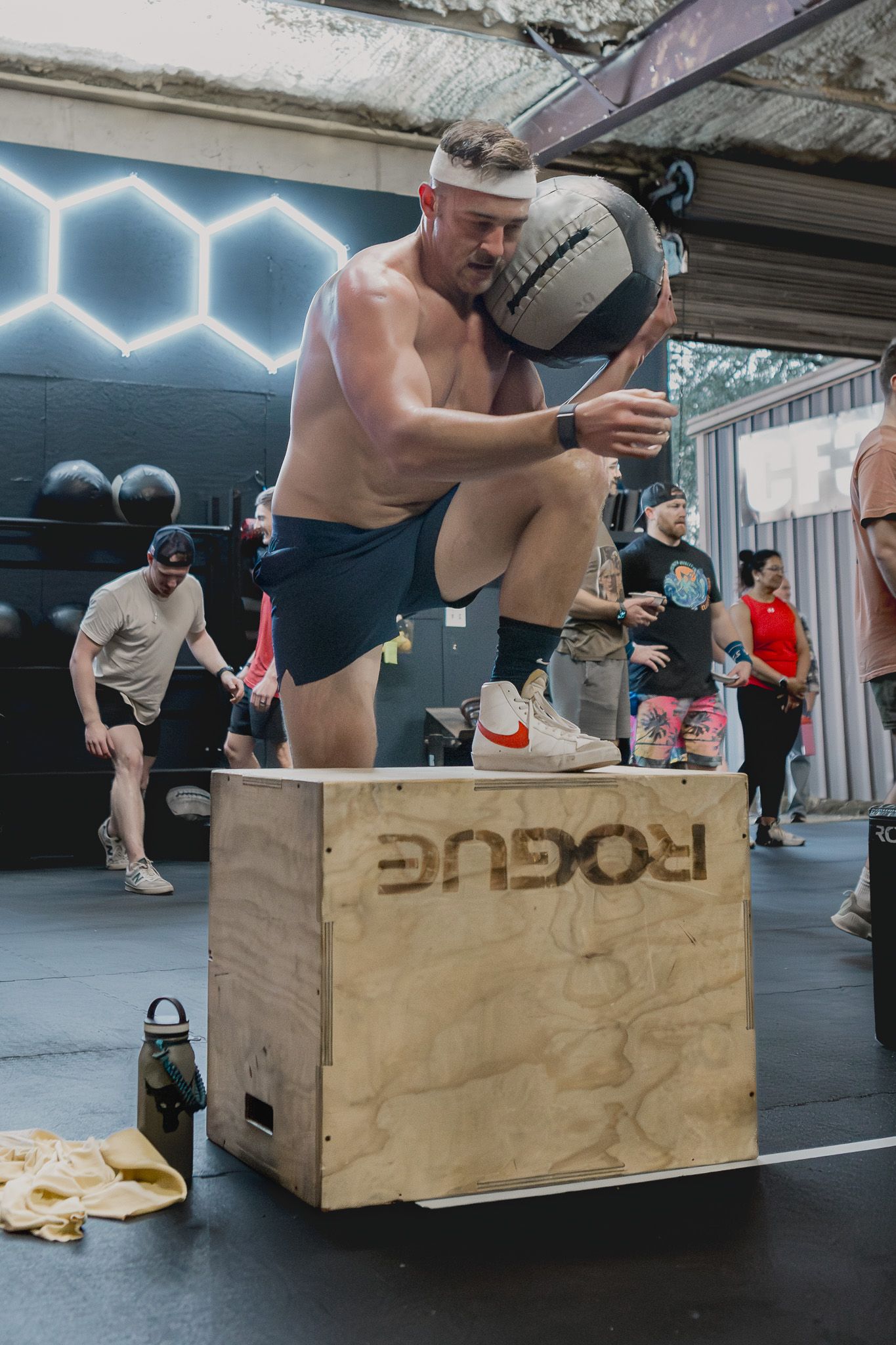 Athlete carrying a medicine ball onto a box at a CrossFit gym