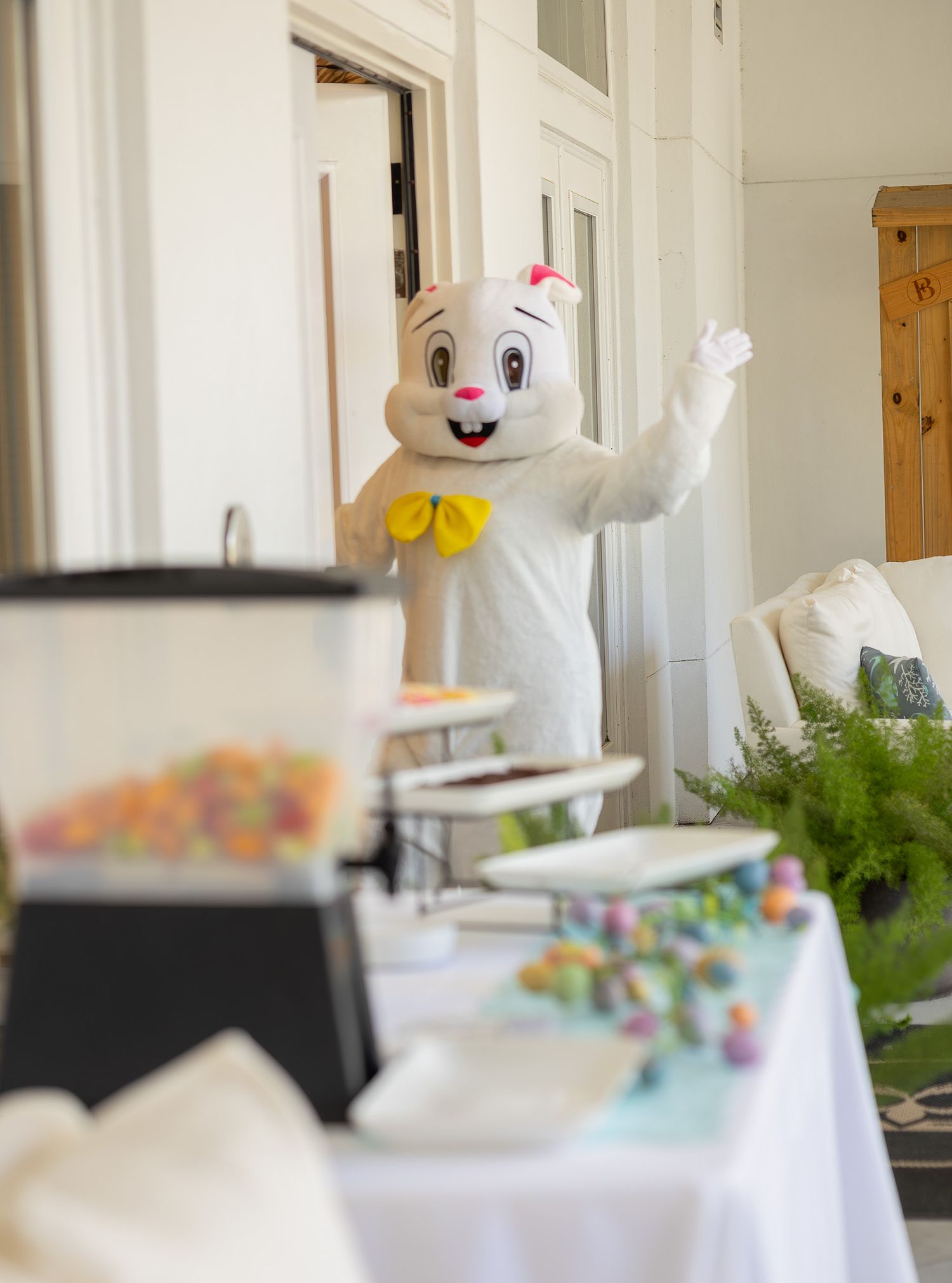 Easter Bunny greeting guests beside a treat table at a spring event