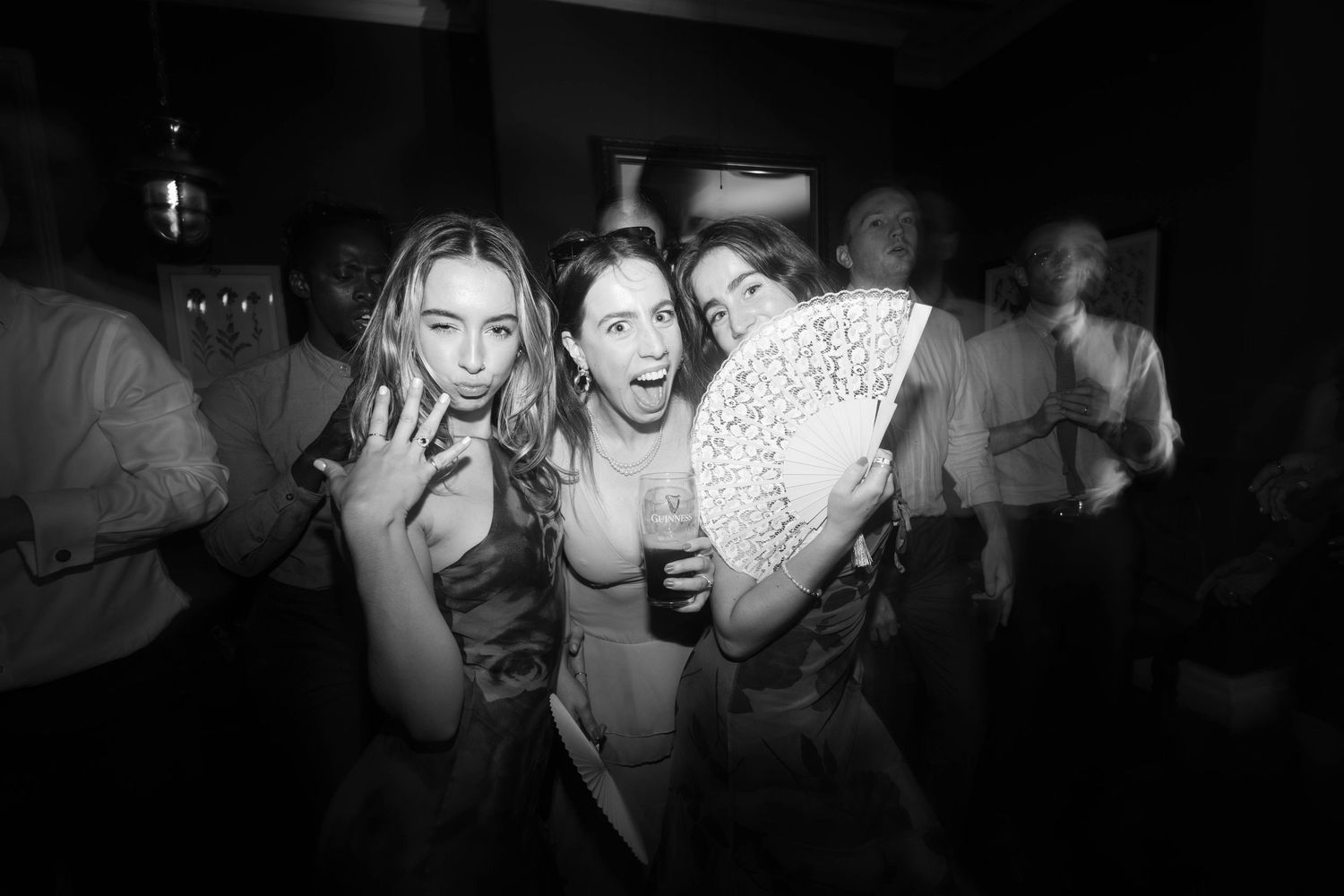 Three women laughing and posing together at a lively black and white wedding reception party. Greater Manchester Wedding Photographer
