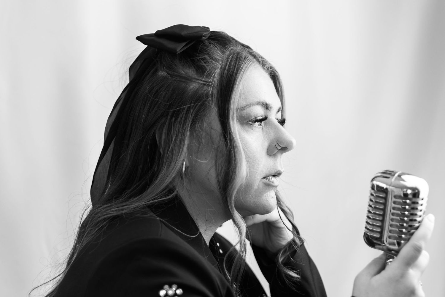 Black and white portrait of woman singing into vintage microphone. Singer in South London