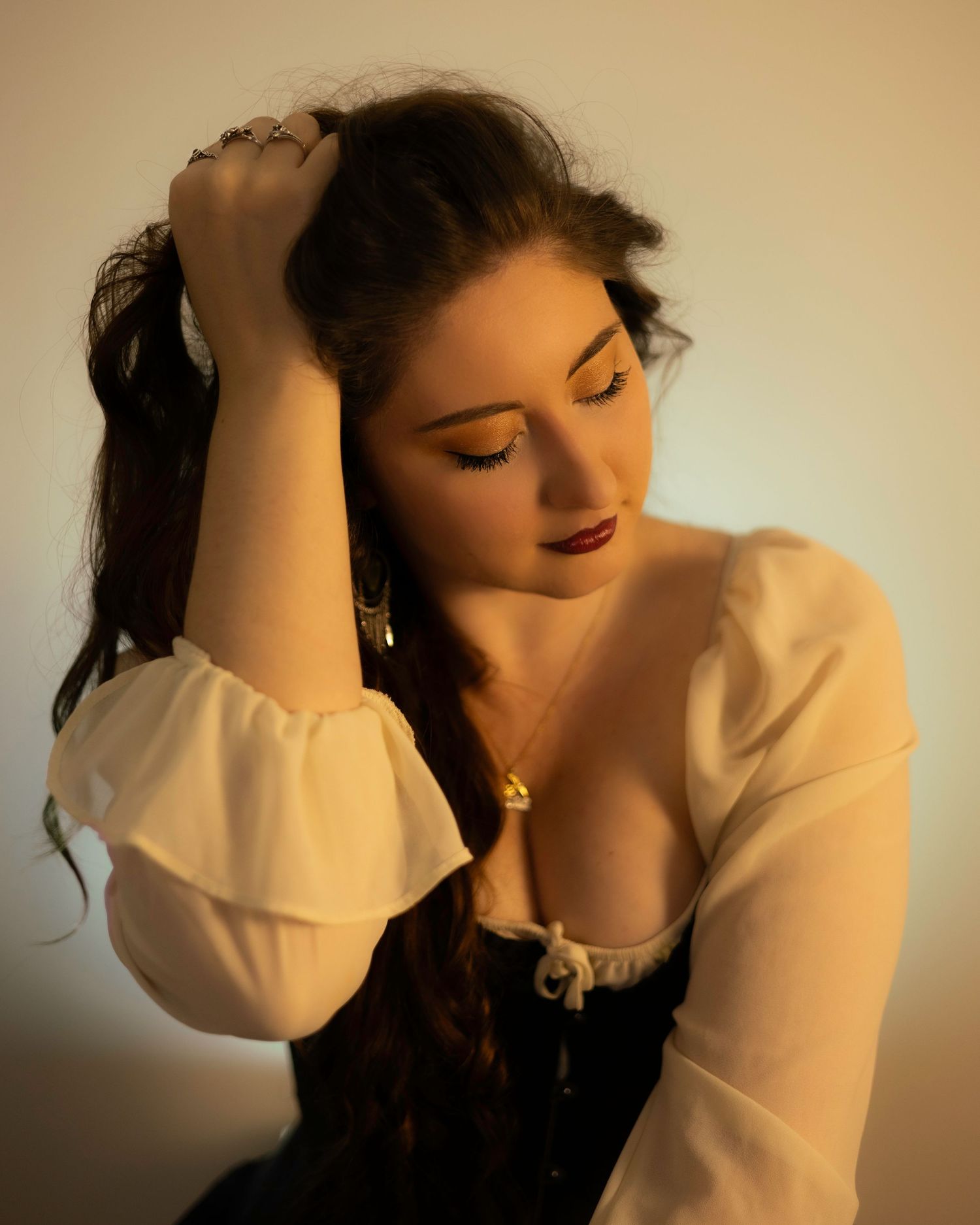 Elegant woman in vintage corset top with gold eye makeup and dark lips posing in warm light. Brand Photography South London