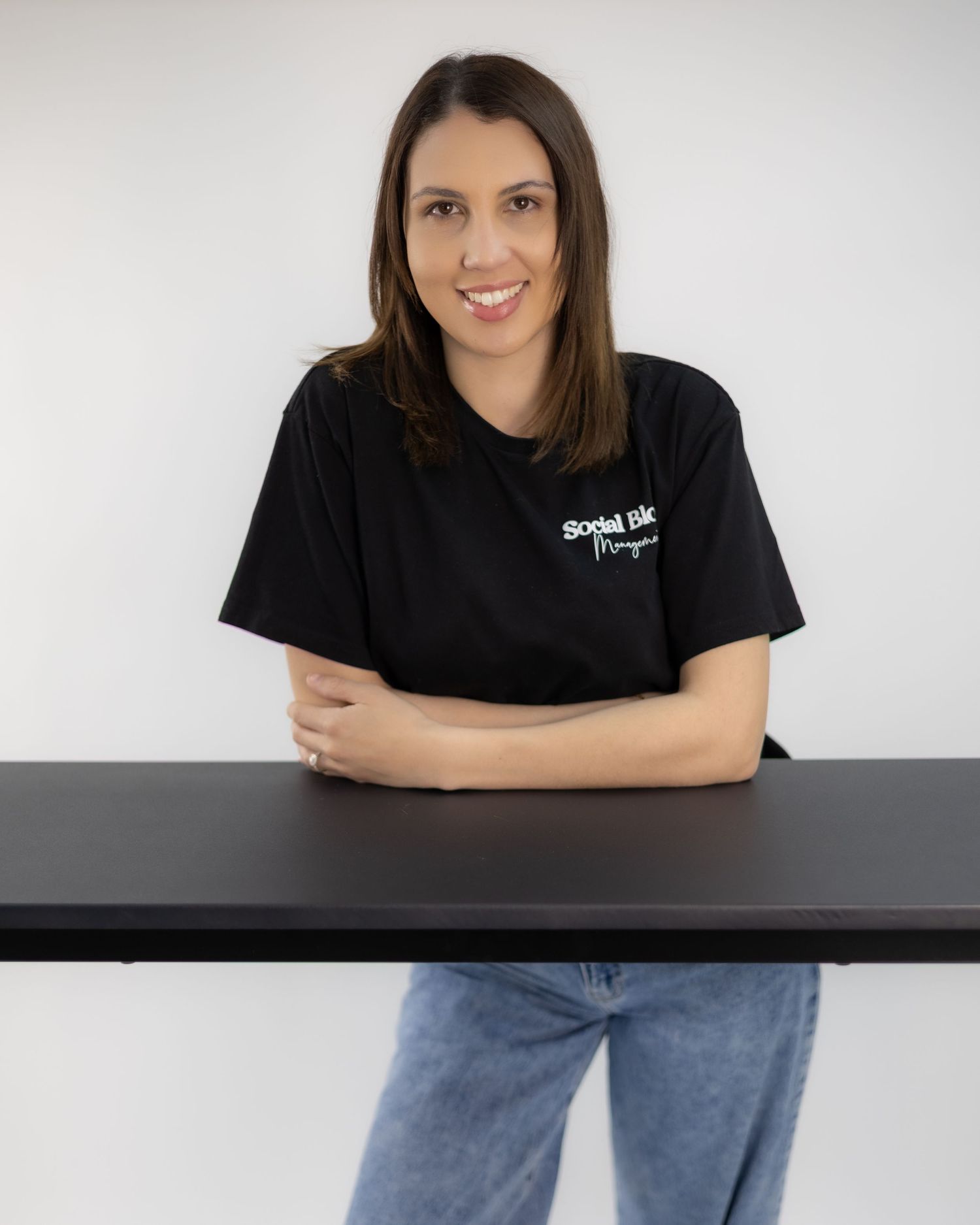 Woman in Social Bloom Management black t-shirt smiling at desk. Brand Photography South London
