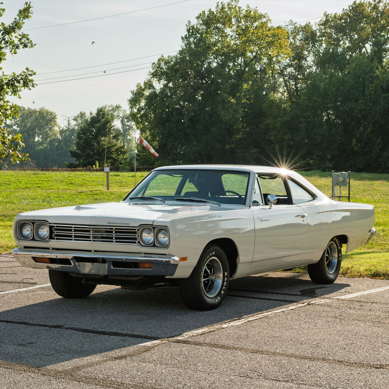 Vintage white 1969 Plymouth Road Runner two-door hardtop muscle car parked on sunny day.