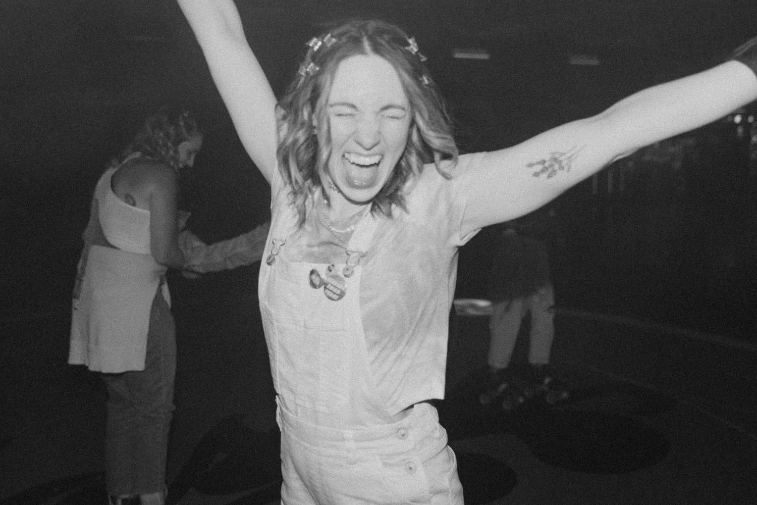 Excited person celebrating with arms raised at an energetic black and white concert event.