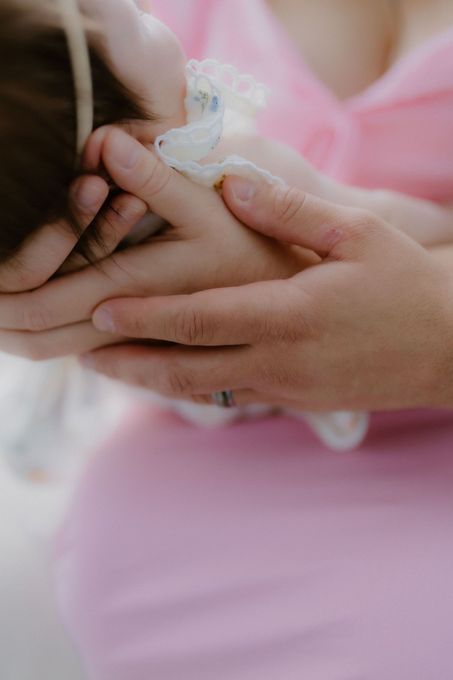 Close-up of parent hands cradling newborn baby head with IV line in color photo.