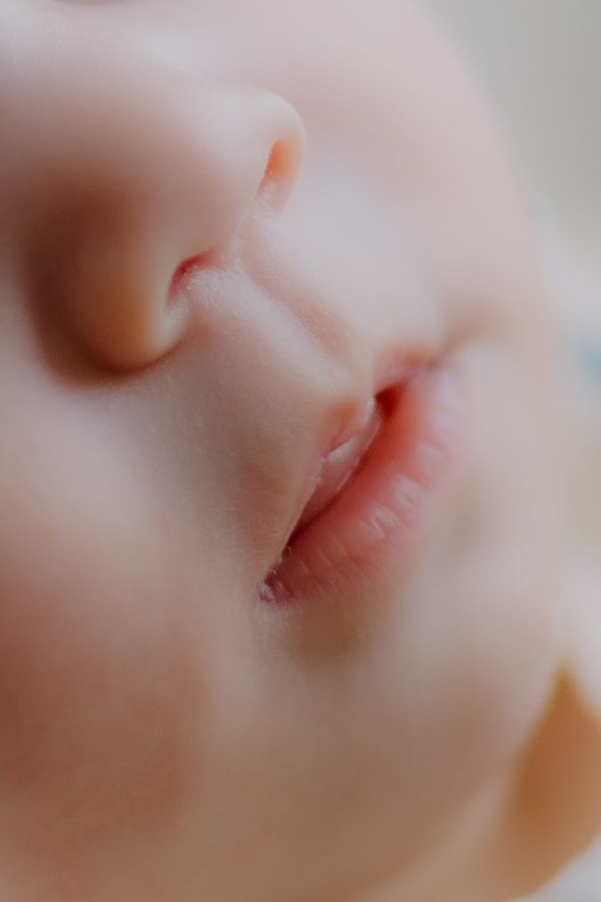 Extreme color macro close-up of a newborn baby's tiny nose and rosebud lips. details