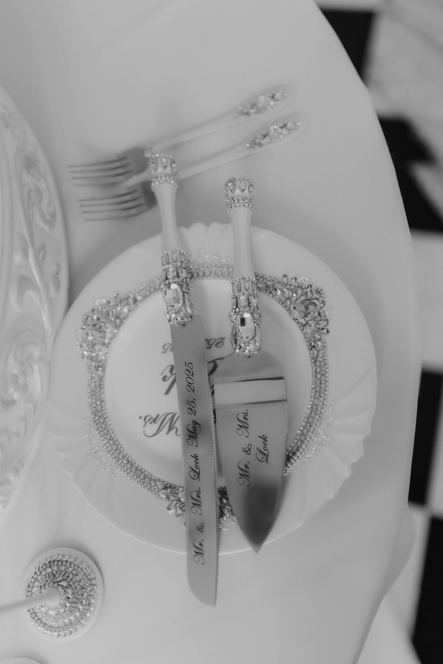 Black and white photo of ornate jeweled cake cutting set engraved with Mr. & Mrs. on decorative plate.