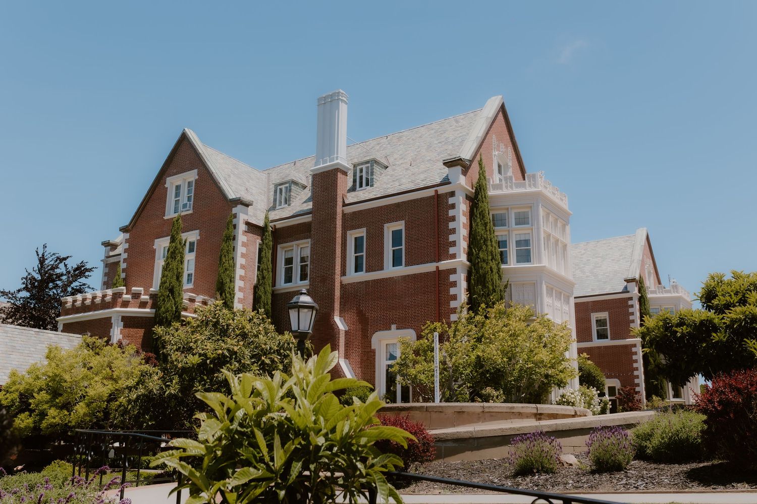 Elegant brick wedding venue mansion with Tudor-style architecture surrounded by lush greenery.