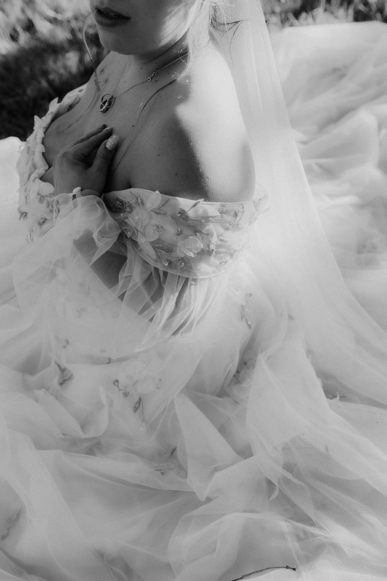 Black and white close-up of bride in floral off-shoulder tulle wedding gown.