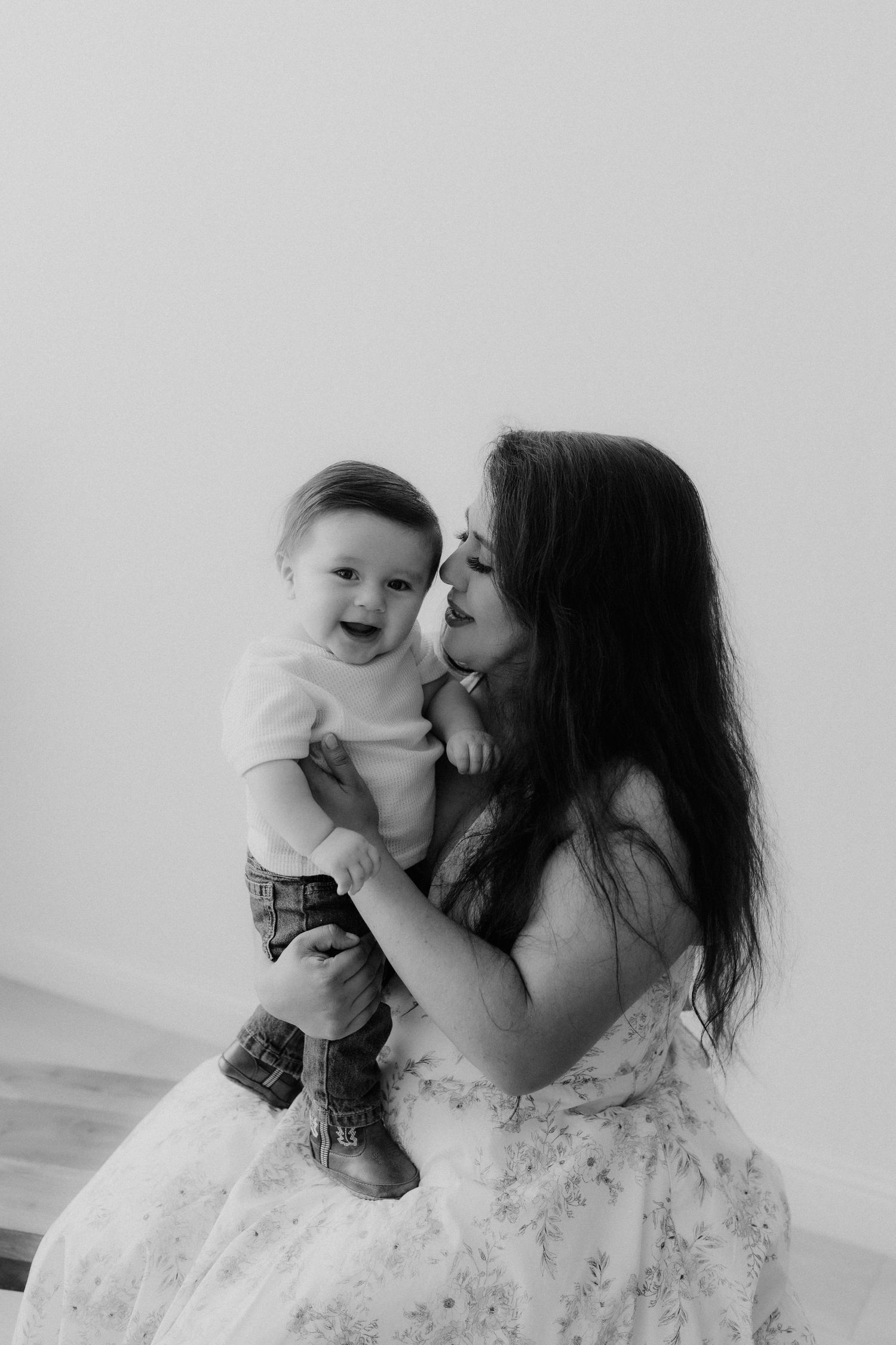 Black and white portrait of a laughing baby boy being held and kissed by his dark-haired mother. mini session, Tulare