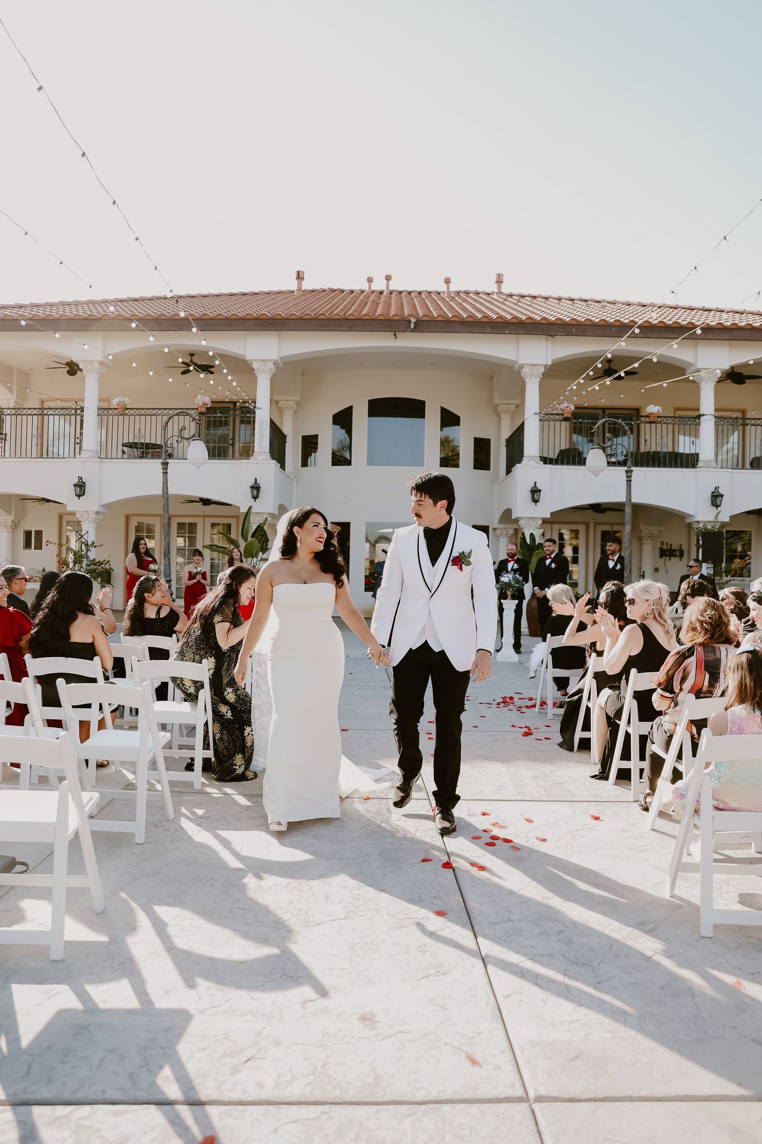 Bride and groom walking down outdoor aisle at elegant venue after ceremony.