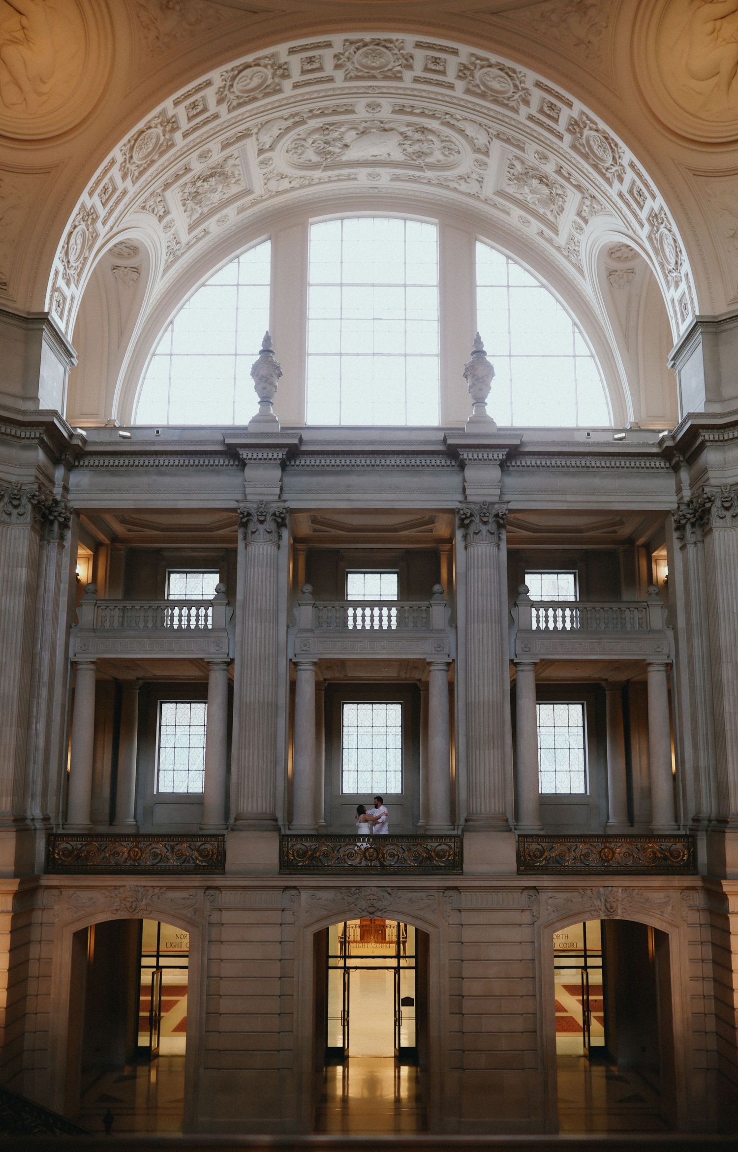 Grand neoclassical interior atrium with ornate arched ceiling, tall columns, and large windows in a historic government building.