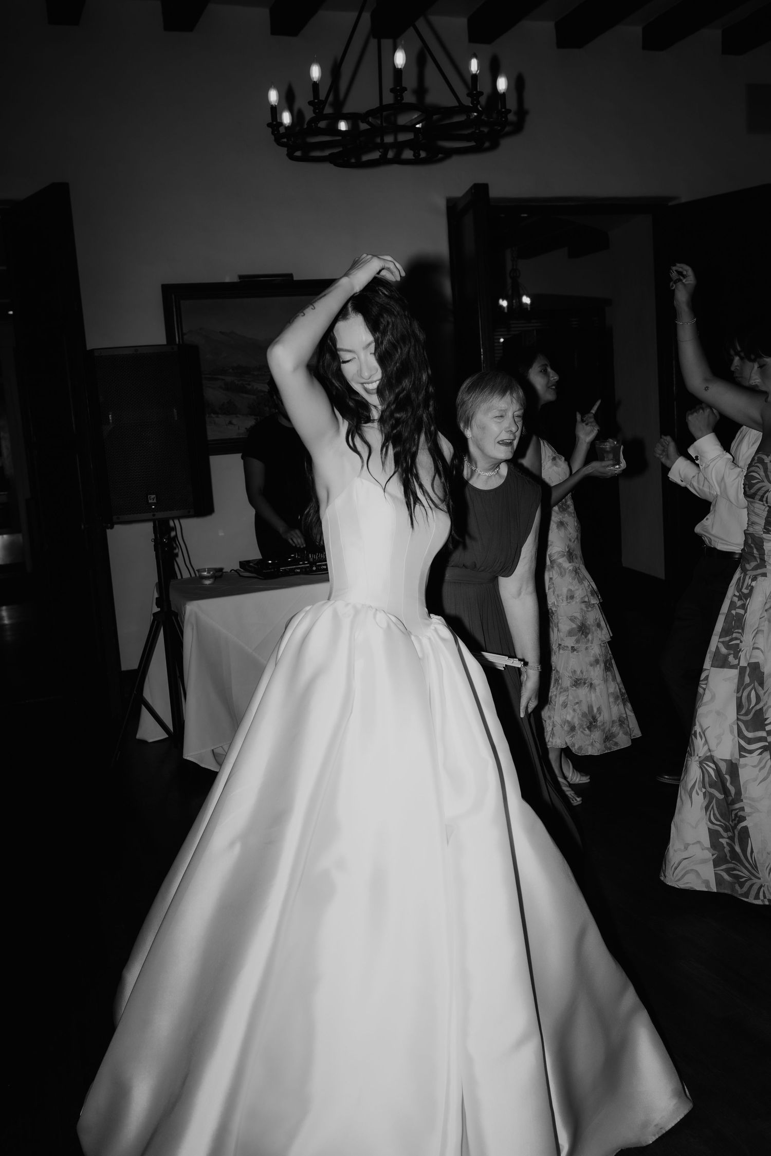 Black and white photo of bride in ballgown dancing joyfully at wedding reception.