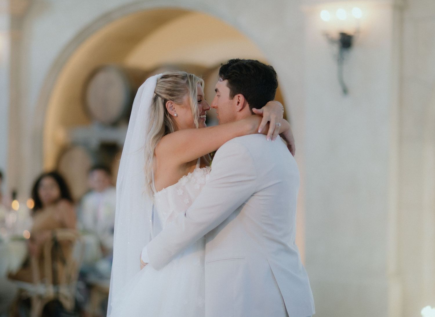 Bride and groom sharing a tender first dance embrace at an elegant wedding reception.