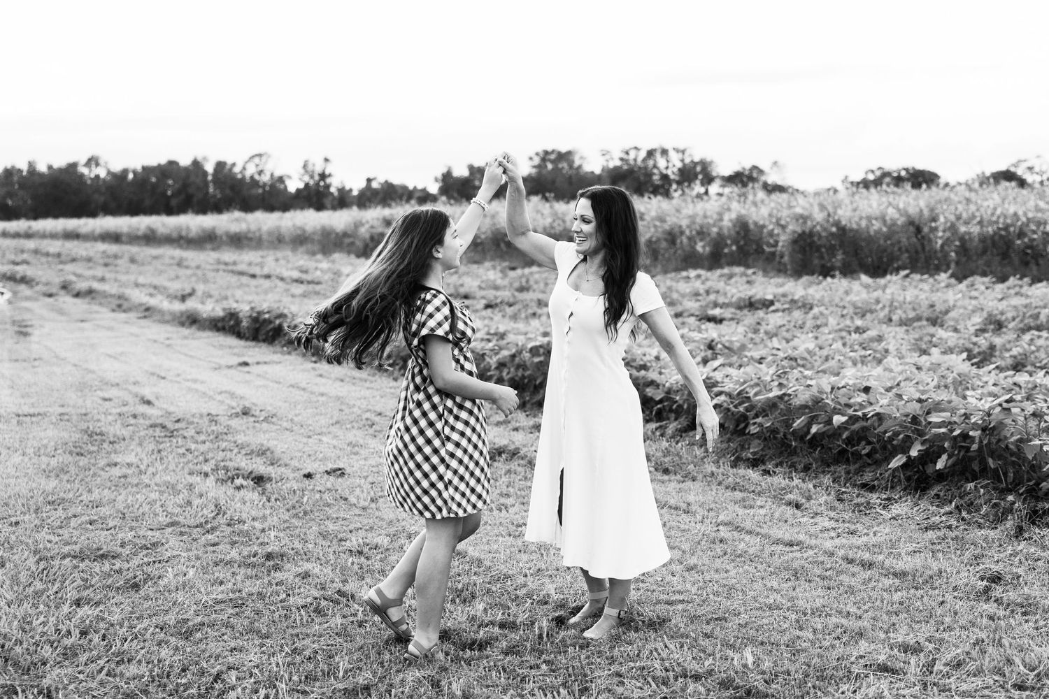 Two girls dancing together in a field, black and white photo.