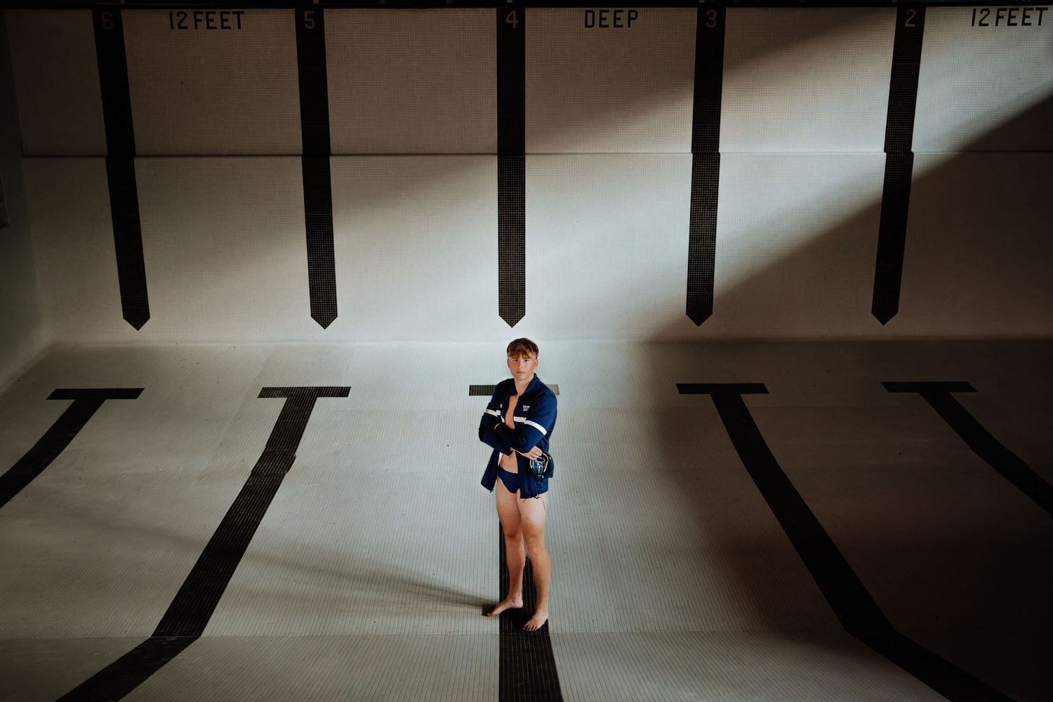 Aerial view of a person standing between large black lane dividers in an indoor swimming pool facility.