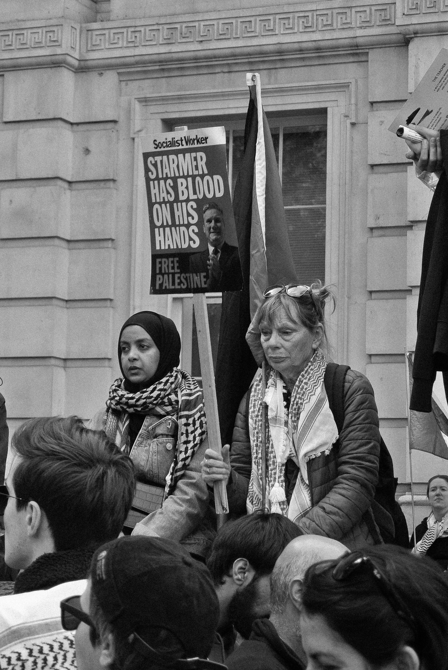 Two women sat watching the crowd at a Palestine demonstration, London