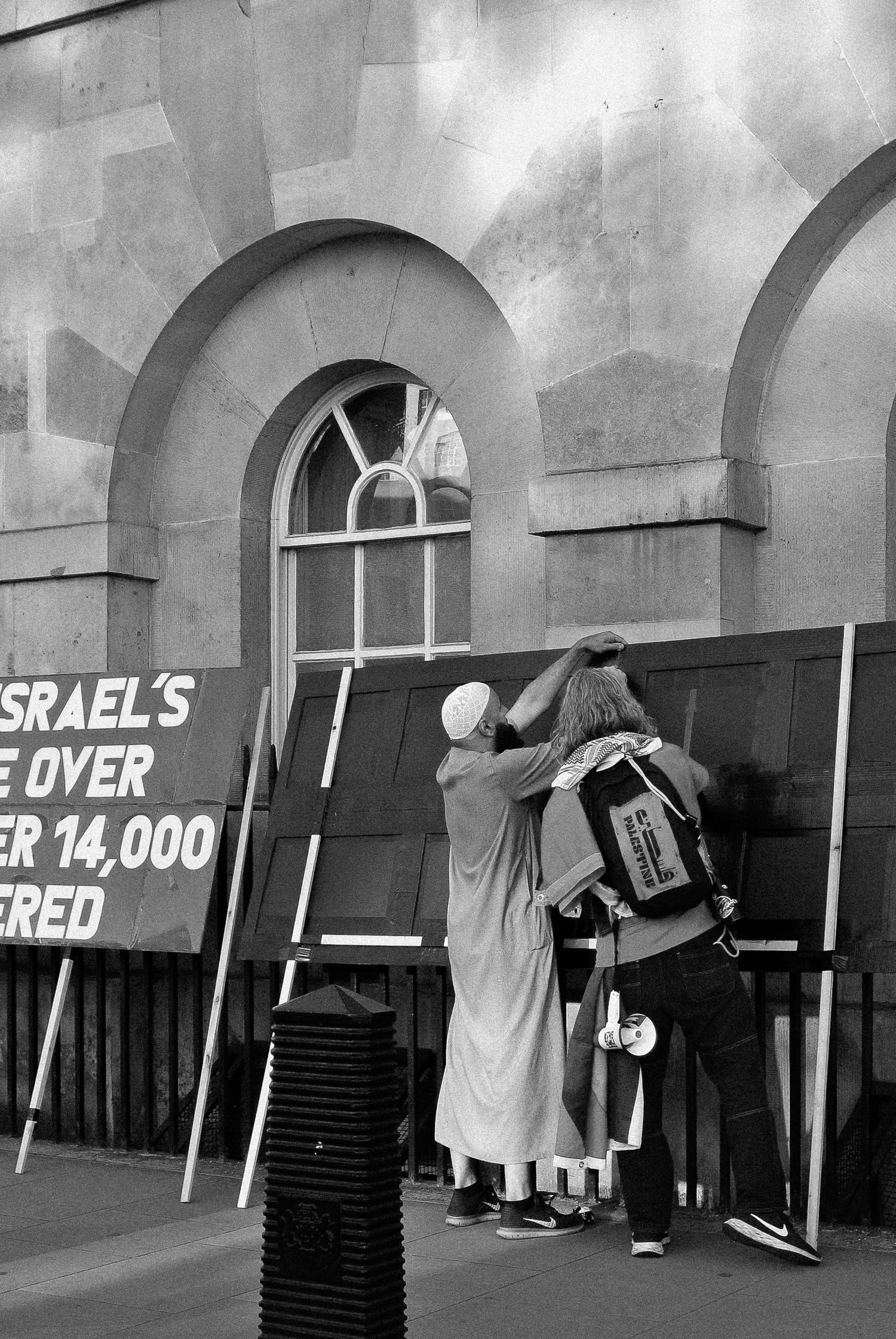 Two men helping each other at a Palestine demonstration, London